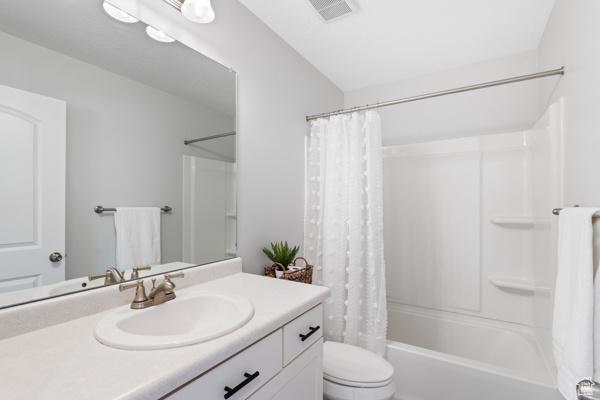 full bathroom with toilet, vanity, and shower / bathtub combination with curtain