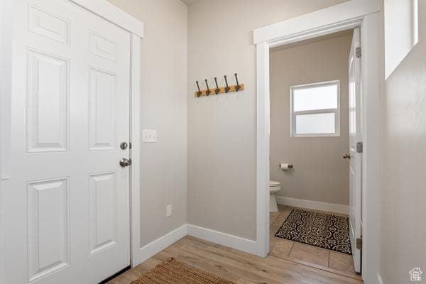 doorway to outside featuring baseboards and light wood-type flooring