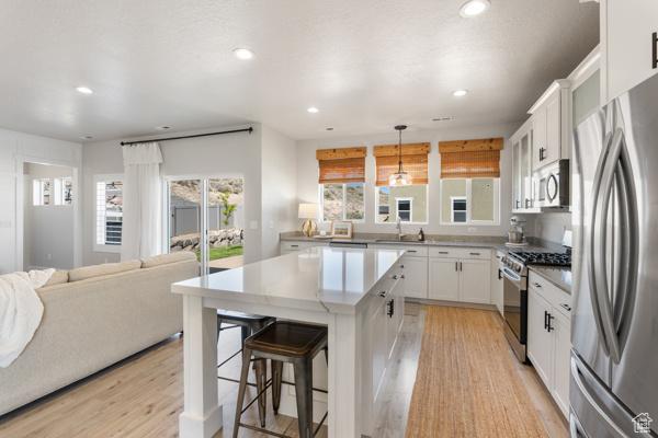kitchen with appliances with stainless steel finishes, light wood finished floors, recessed lighting, white cabinetry, and light countertops