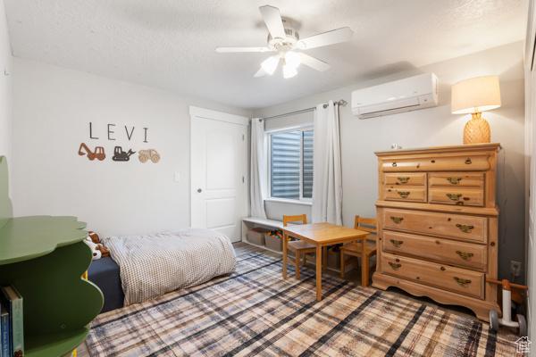 bedroom with an AC wall unit and ceiling fan