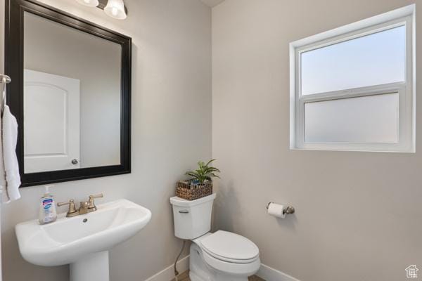 bathroom featuring baseboards, a sink, and toilet
