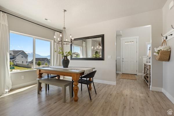 dining room with a chandelier, light wood finished floors, and baseboards
