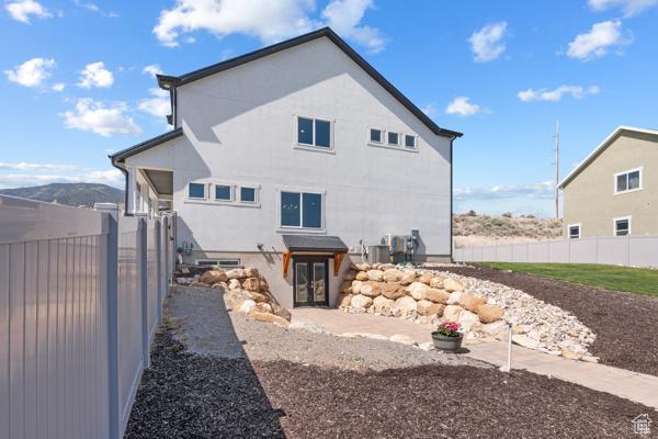 rear view of house featuring fence, french doors, and stucco siding
