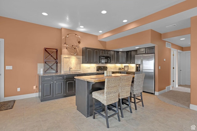 395 S 200 E, Willard, UT 84340 - kitchen with stainless steel fridge with ice dispenser, black microwave, a kitchen island, a kitchen bar, and baseboards