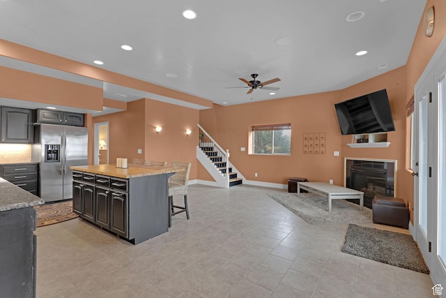 395 S 200 E, Willard, UT 84340 - kitchen with stainless steel fridge with ice dispenser, a kitchen bar, a glass covered fireplace, ceiling fan, and open floor plan