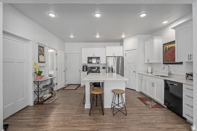 kitchen with black appliances, a sink, a center island, a kitchen bar, and white cabinets