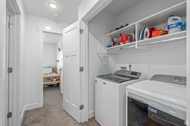 laundry area featuring washing machine and dryer, light carpet, and baseboards