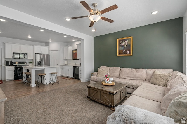 living area with recessed lighting, a ceiling fan, wood finished floors, and baseboards