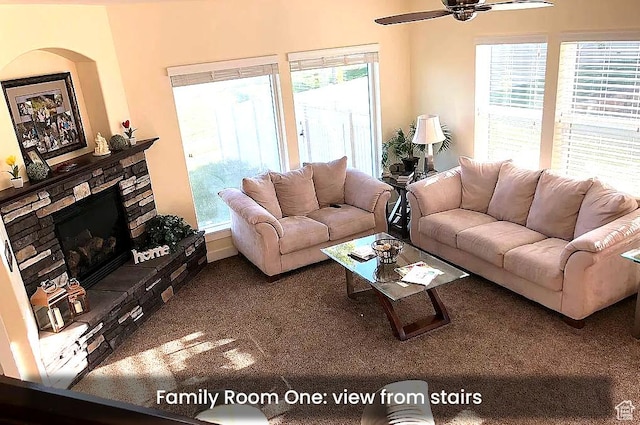 living room with ceiling fan, plenty of natural light, a fireplace, and carpet