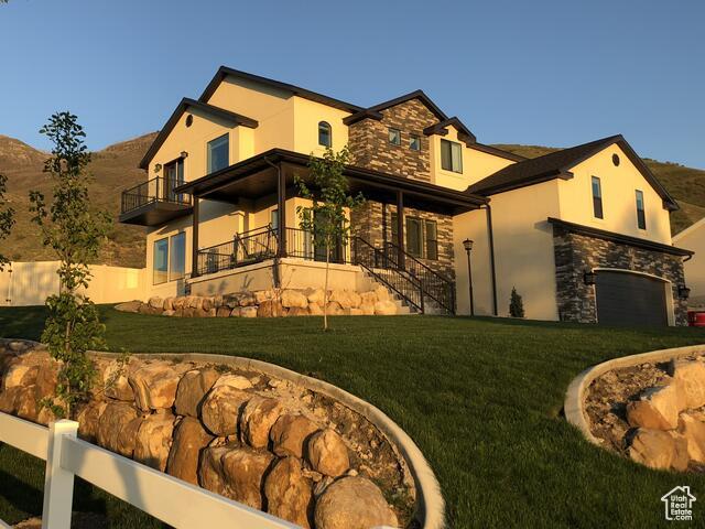 view of property exterior with stucco siding, stone siding, a balcony, and stairway
