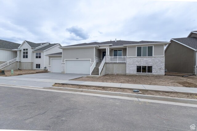 3148 N 2875 W Unit 29, Plain City, UT 84404 - view of front of house with driveway, stairway, an attached garage, and stone siding