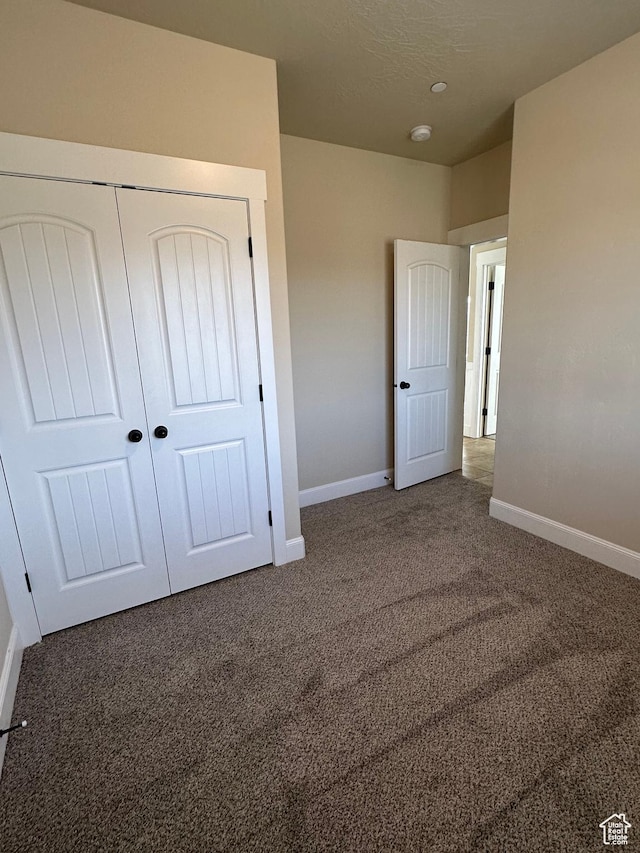 unfurnished bedroom with carpet flooring, baseboards, and a closet