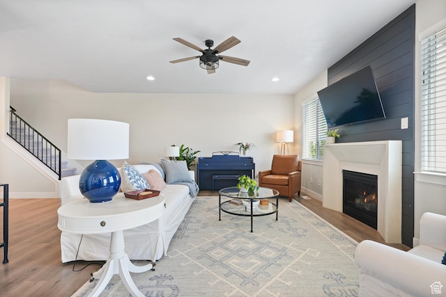 living room featuring wood finished floors, ceiling fan, stairway, recessed lighting, and a fireplace
