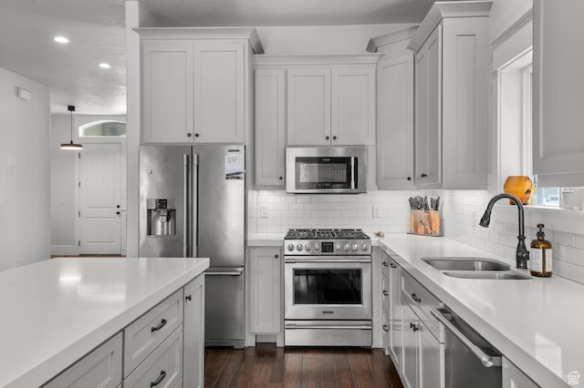 kitchen with stainless steel appliances, a sink, light countertops, backsplash, and recessed lighting