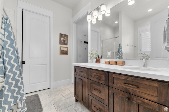 bathroom featuring a shower stall, double vanity, and baseboards