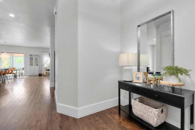 corridor with wood finished floors, baseboards, and recessed lighting