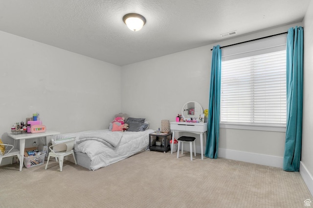 carpeted bedroom with a textured ceiling and baseboards