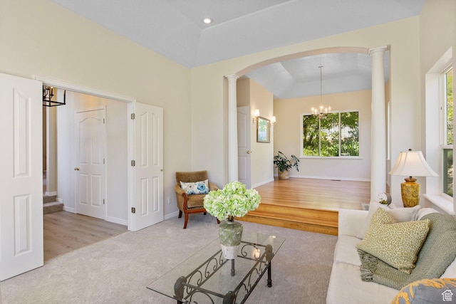 living area featuring arched walkways, decorative columns, carpet flooring, a tray ceiling, and a chandelier