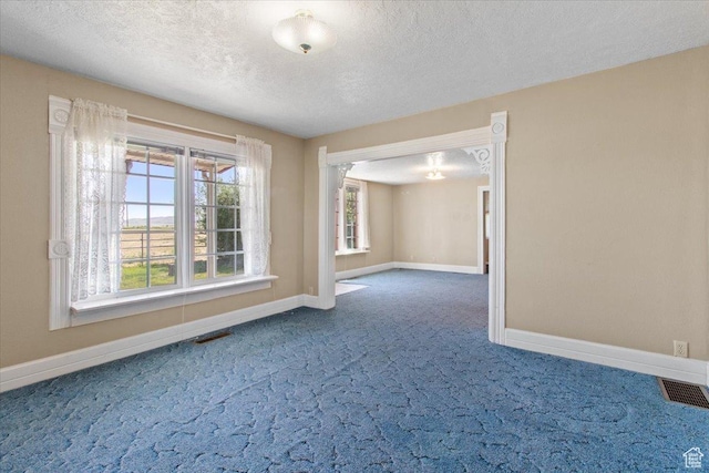 unfurnished room with dark colored carpet, baseboards, a textured ceiling, and a chandelier