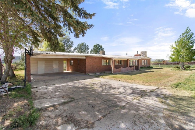 single story home featuring a chimney, concrete driveway, an attached carport, and brick siding
