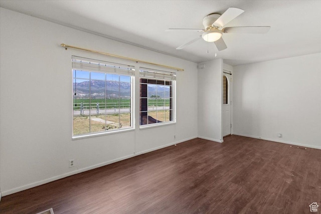 spare room with wood finished floors, baseboards, ceiling fan, and a mountain view