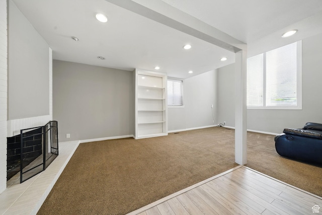 living area with light carpet, light wood finished floors, healthy amount of natural light, baseboards, and recessed lighting