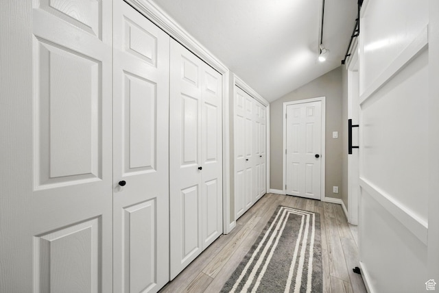 hall with lofted ceiling and light wood-type flooring