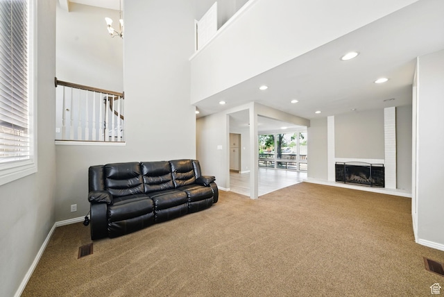 carpeted living area featuring a chandelier, baseboards, recessed lighting, and a fireplace with raised hearth