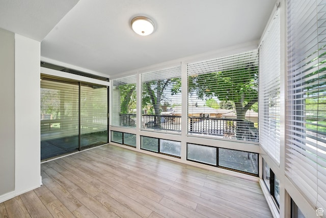 unfurnished sunroom featuring wood finished floors and a water view