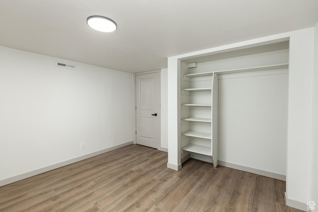 unfurnished bedroom featuring wood finished floors, baseboards, and a closet
