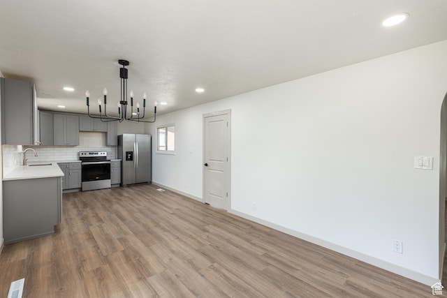 kitchen with appliances with stainless steel finishes, gray cabinetry, light countertops, a chandelier, and recessed lighting