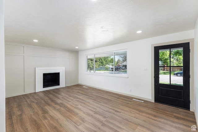 unfurnished living room with healthy amount of natural light, wood finished floors, recessed lighting, and a fireplace
