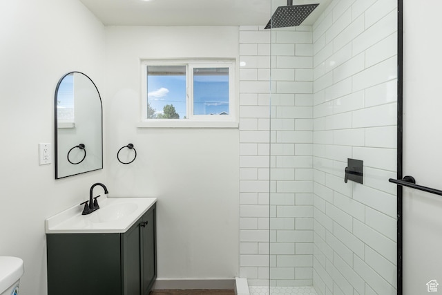 bathroom with tiled shower, vanity, and toilet
