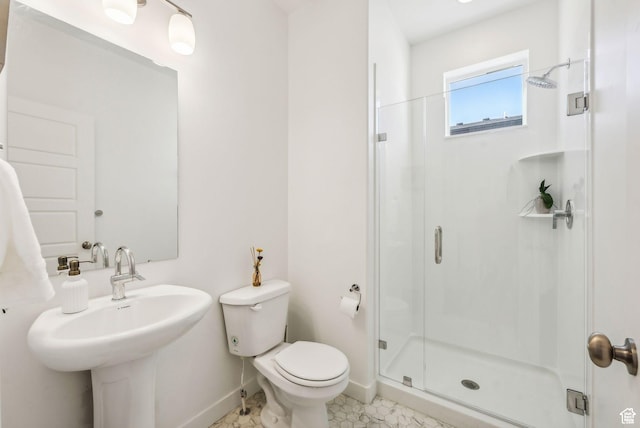 bathroom with baseboards, a shower stall, toilet, and a sink