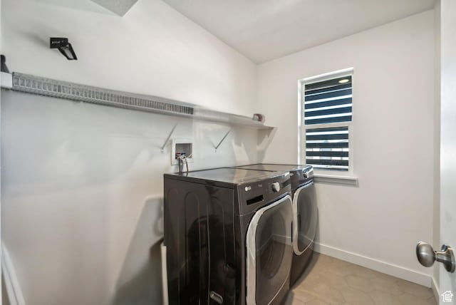 laundry area featuring washer and dryer, baseboards, and light tile patterned floors