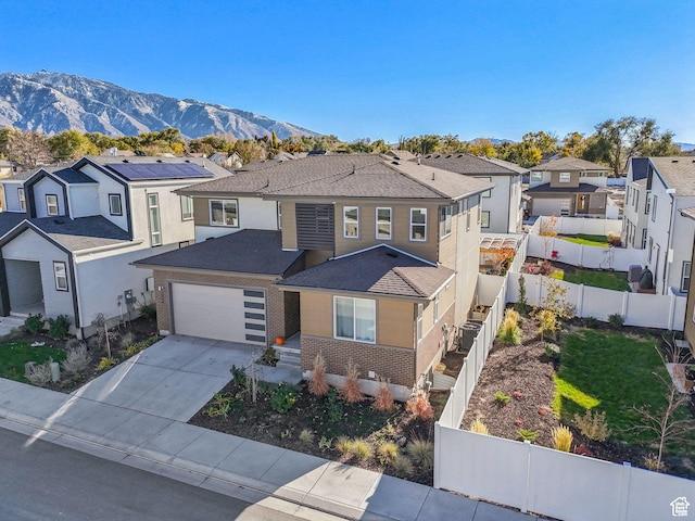 view of front of property with a residential view, fence, driveway, a mountain view, and roof with shingles