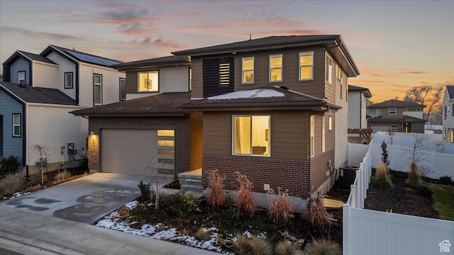 view of front facade featuring concrete driveway, fence, brick siding, and central AC unit