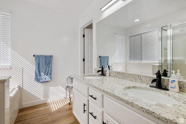 full bathroom featuring double vanity, wood finished floors, a shower stall, and baseboards