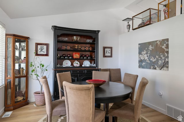 dining space featuring light wood-type flooring, lofted ceiling, and baseboards