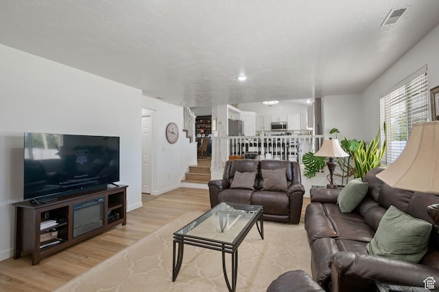 living room with stairs, light wood-type flooring, and baseboards