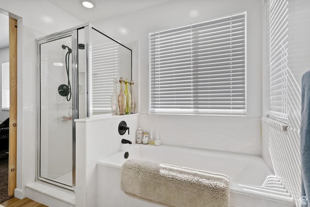 bathroom featuring a shower stall, a bath, and wood finished floors