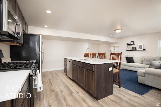 6637 W Terrace Sky Ln, West Jordan, UT 84081 - kitchen featuring appliances with stainless steel finishes, a sink, dark brown cabinets, open floor plan, and a kitchen bar