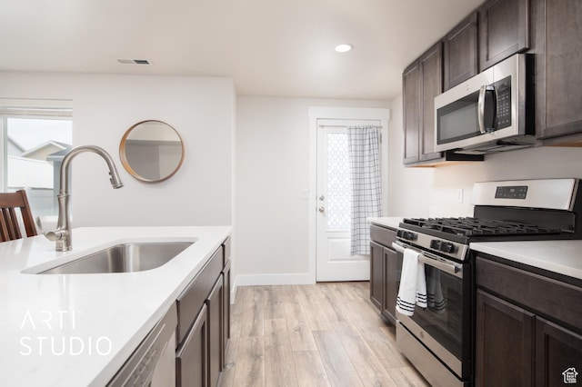 6637 W Terrace Sky Ln, West Jordan, UT 84081 - kitchen with stainless steel appliances, a sink, dark brown cabinets, light wood-type flooring, and light countertops