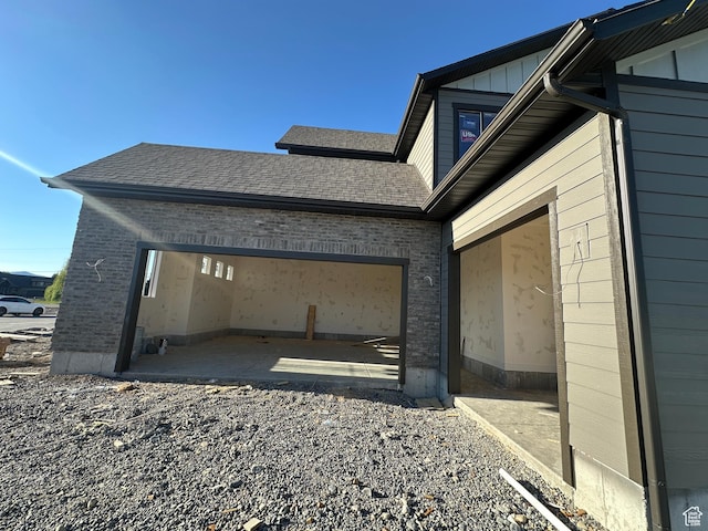 1768 N Siena Cir Unit 12, Pleasant Grove, UT 84062 - view of property exterior with a garage, brick siding, a shingled roof, and board and batten siding