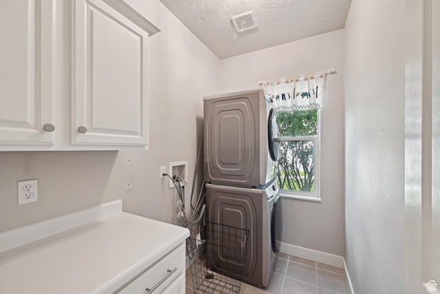 13994 S New Saddle Rd, Draper, UT 84020 - washroom with cabinet space, stacked washer / drying machine, a textured ceiling, baseboards, and light tile patterned floors