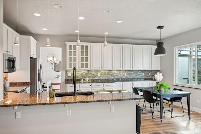 13994 S New Saddle Rd, Draper, UT 84020 - kitchen featuring appliances with stainless steel finishes, a sink, decorative backsplash, dark stone countertops, and white cabinetry