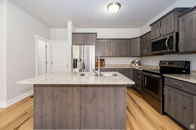 466 W 1595 N Unit 45-103, Logan, UT 84341 - kitchen featuring appliances with stainless steel finishes, a sink, light wood-style flooring, dark brown cabinets, and a center island with sink