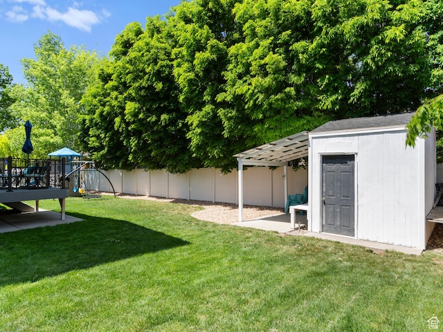 view of yard featuring a playground, an outdoor structure, and a storage unit