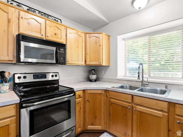 kitchen featuring stainless steel range with electric stovetop, a sink, light countertops, and light brown cabinetry