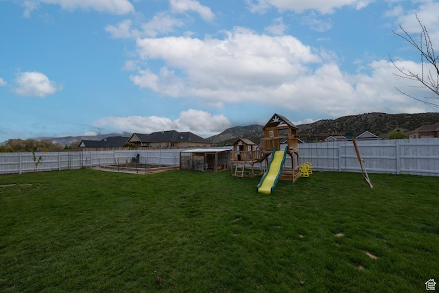 view of yard featuring a garden, a playground, and a mountain view